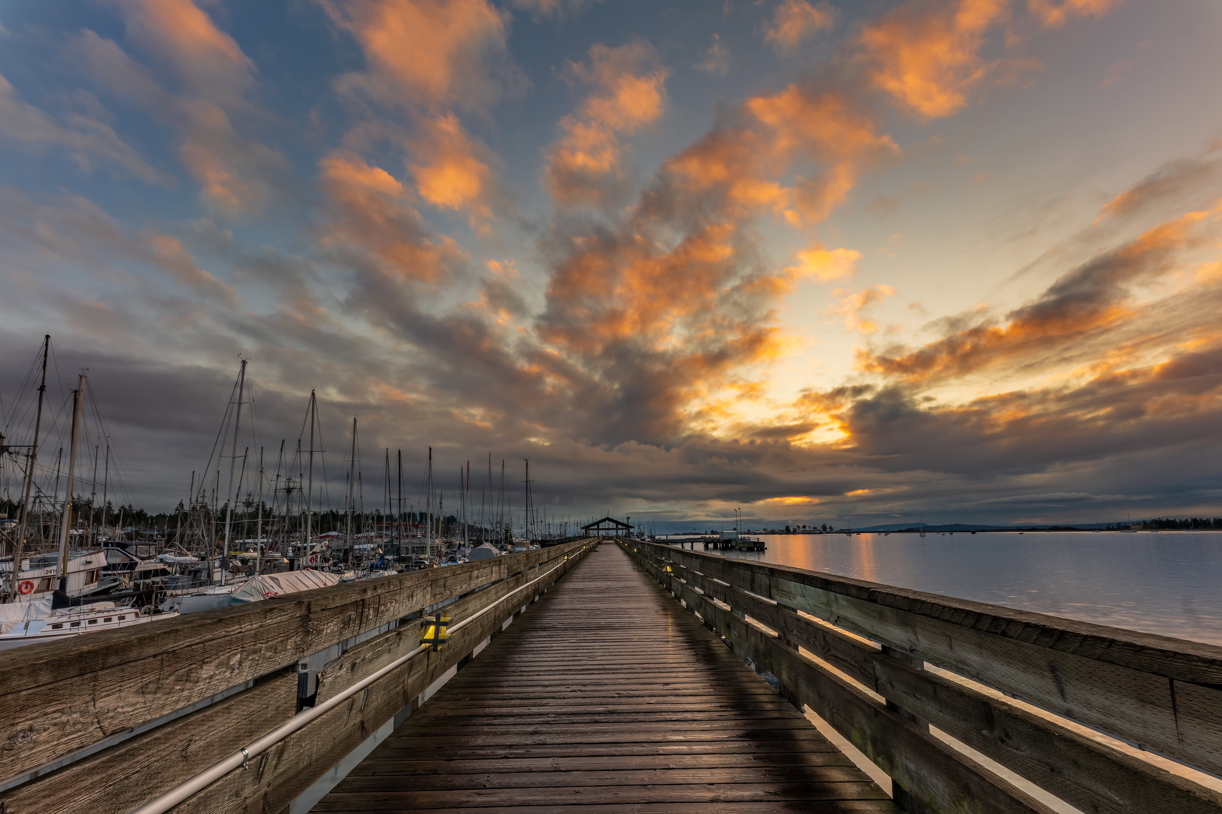 Fisherman's Wharf Boardwalk wall art showing sunrise over Goose Spit from the boardwalk railing, Comox Harbour, BC, by James Wheeler.