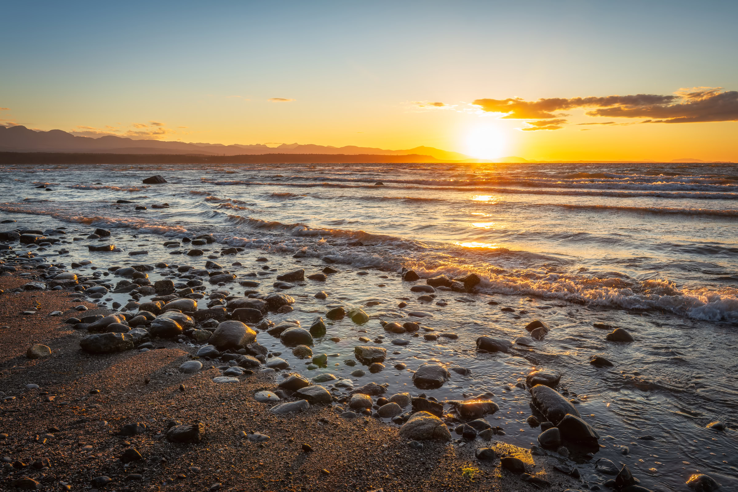 Fossil Beach Hornby Island print showing high tide waves over wet stones as the sun sets over Vancouver Island, BC, by James Wheeler.