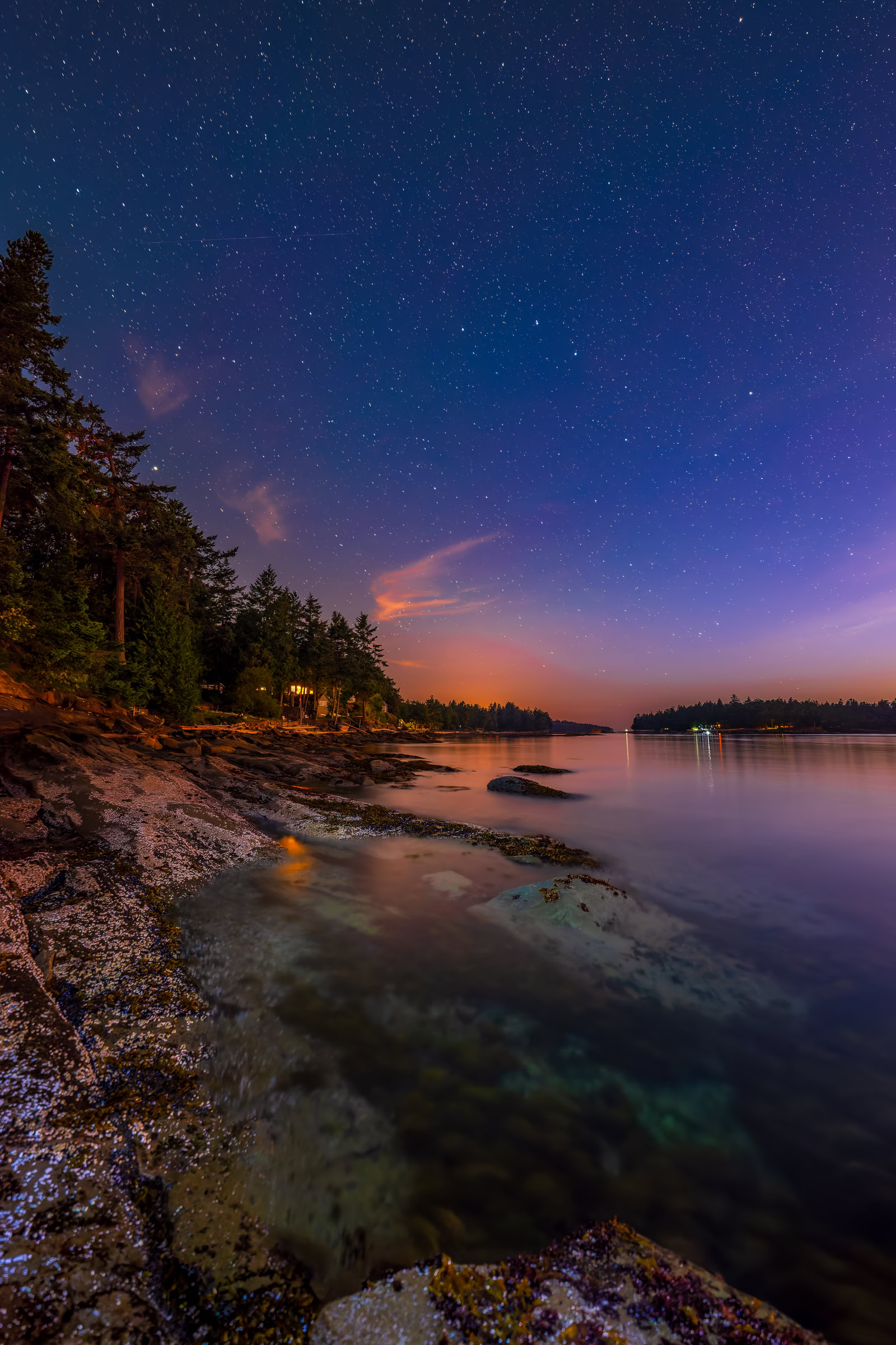 Galiano Island night sky wall art of stars over a barnacled rock shoreline and calm water, the glow of Vancouver low on the horizon, BC, by James Wheeler.