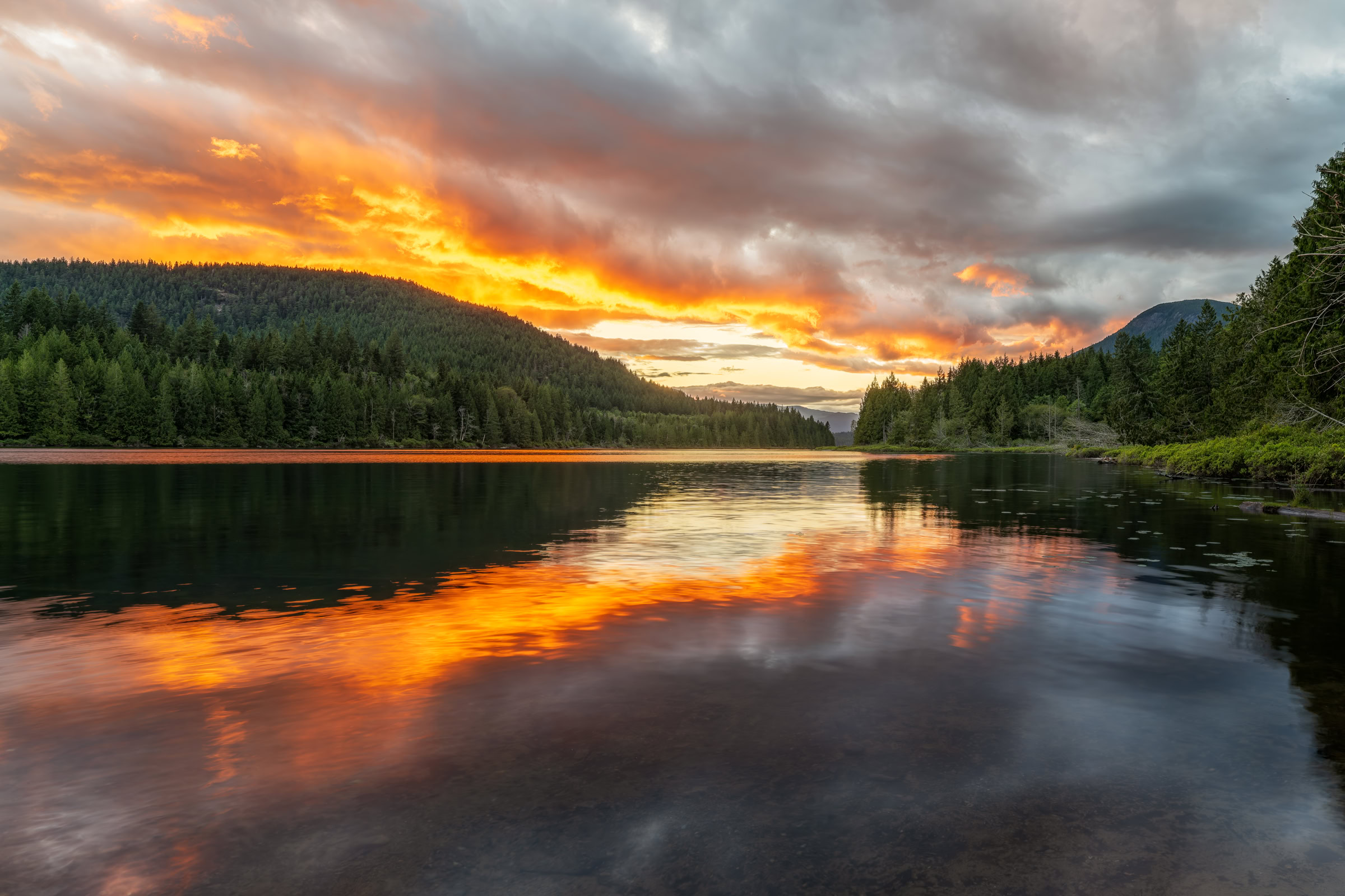 Sunshine Coast BC lake sunset print of orange and red clouds mirrored in Inland Lake between forested hills near Powell River, BC, by James Wheeler.