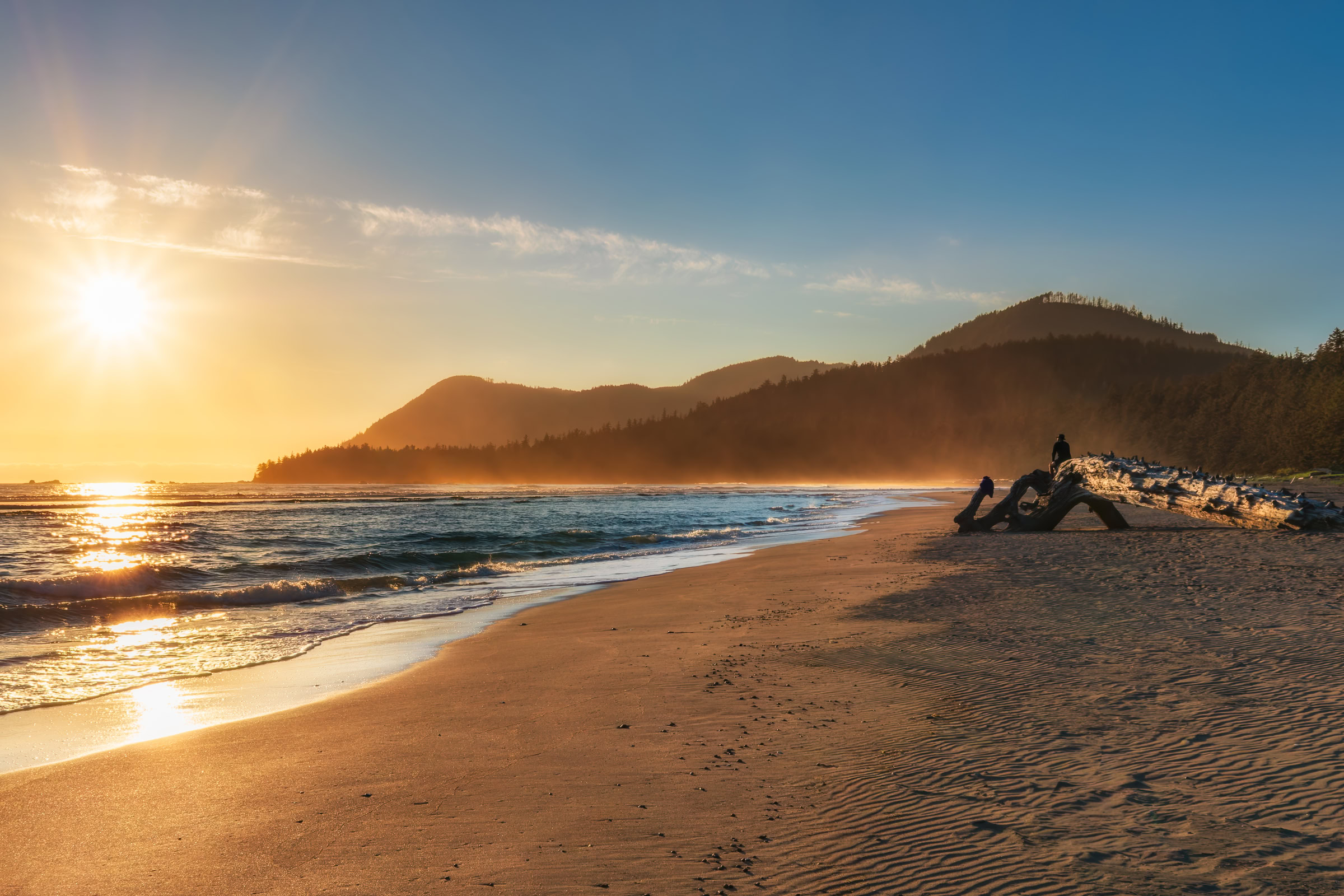 Raft Cove Vancouver Island print showing a wide sand beach at sunset with surf, driftwood and a misty forested headland, north Vancouver Island, BC, by James Wheeler.