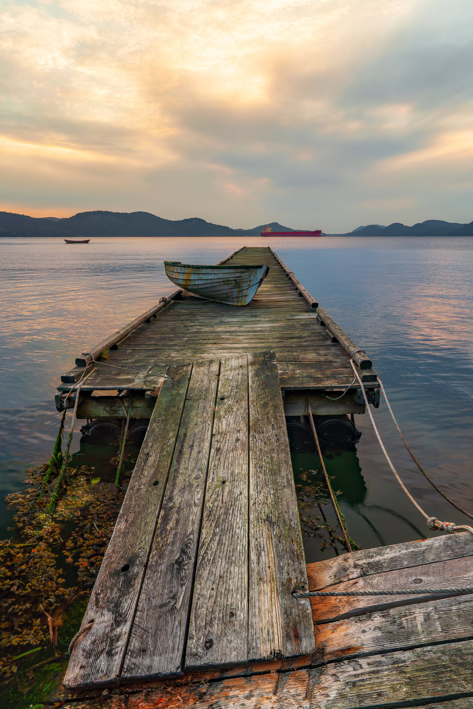 Saturna Island BC wall art of an old rowboat on a weathered dock at evening light, Pender Island across Plumper Sound in the Gulf Islands, by James Wheeler.